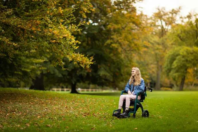 a woman sitting on top of a green chair in a park